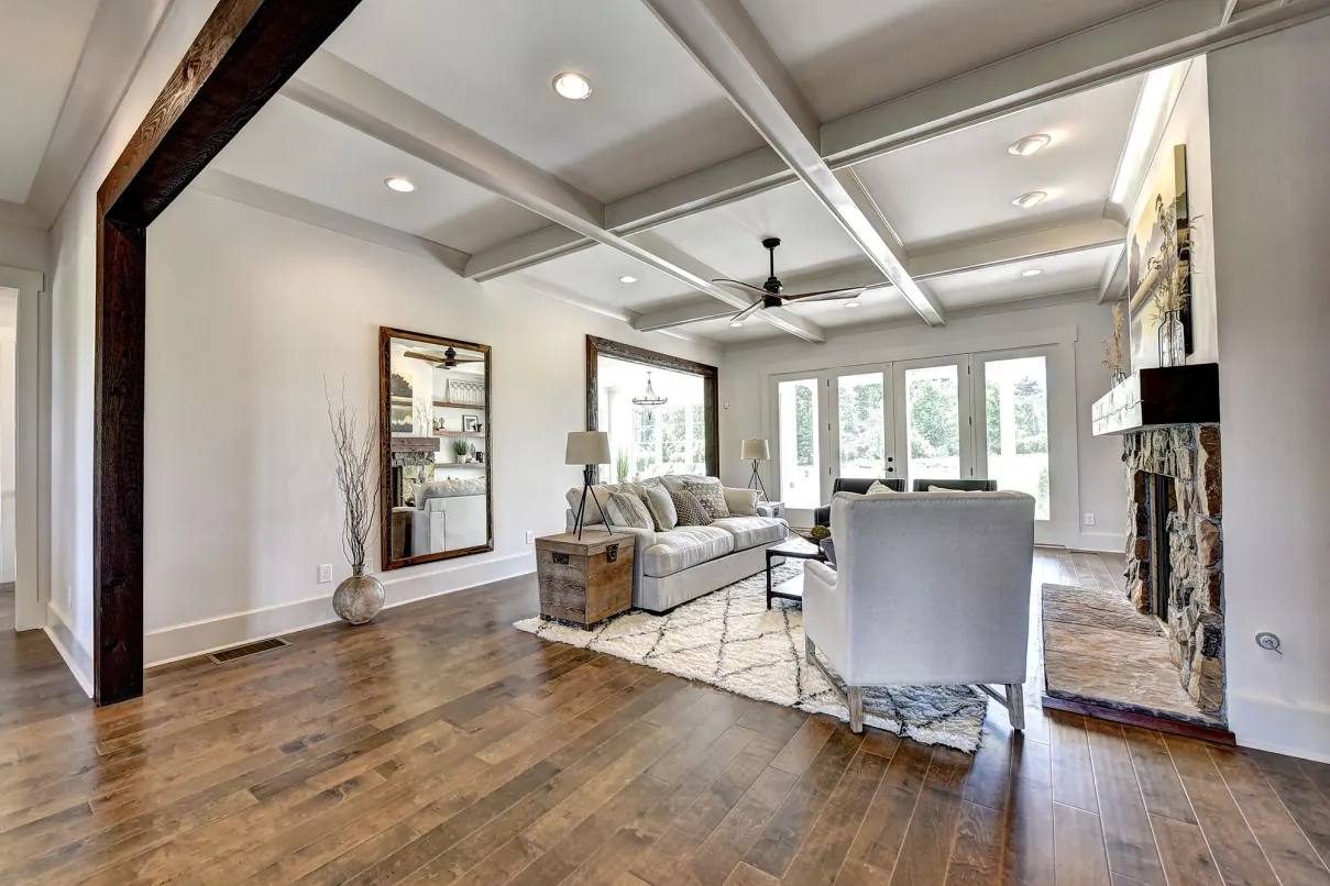 Open living room with coffered ceiling and stone fireplace